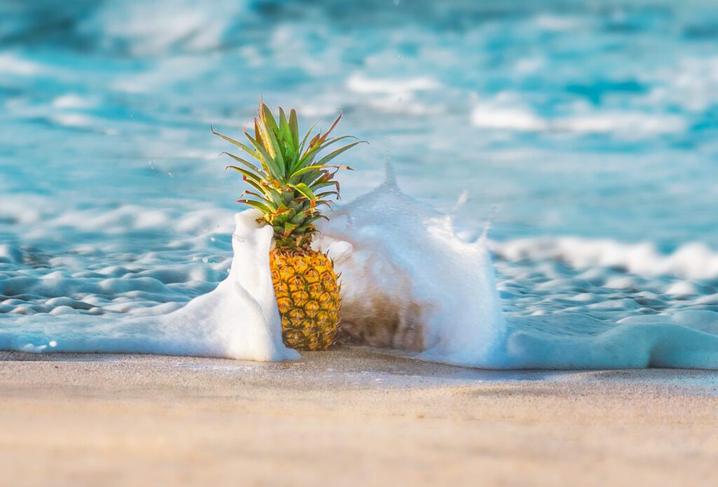 Maui Holiday Gift Guide: Pineapple being blanketed by small wave on Kapalua Beach in Maui, Hawaii.