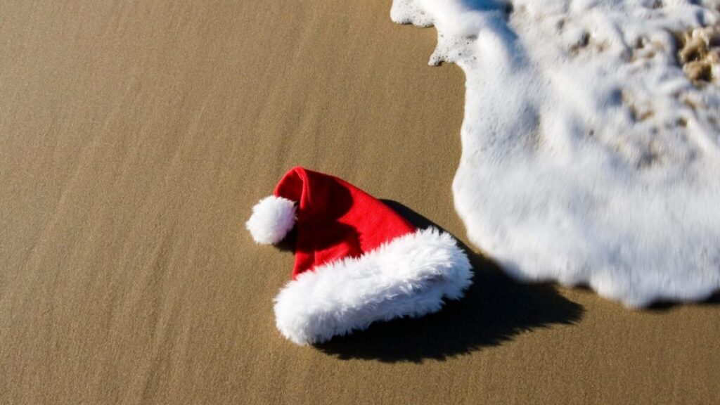 Santa hat on the beach by the water.