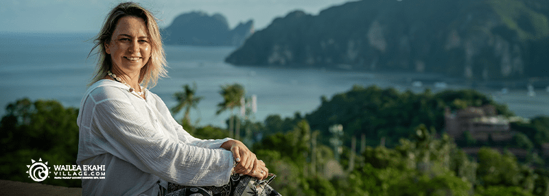 Woman sitting and smiling at camera with view of Maui in the background from up above