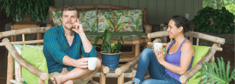 Man and woman sitting outside and drinking coffee looking out at the view